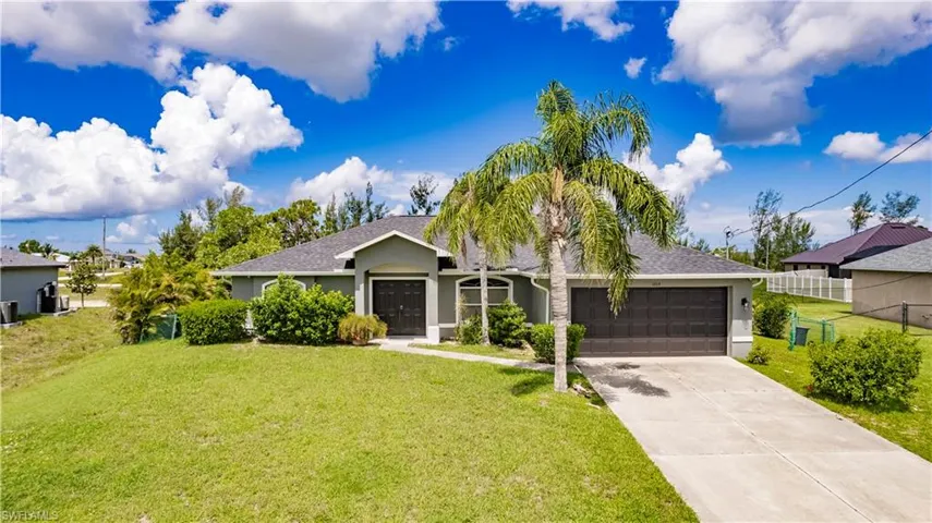 Ranch-style house featuring a garage and a front lawn