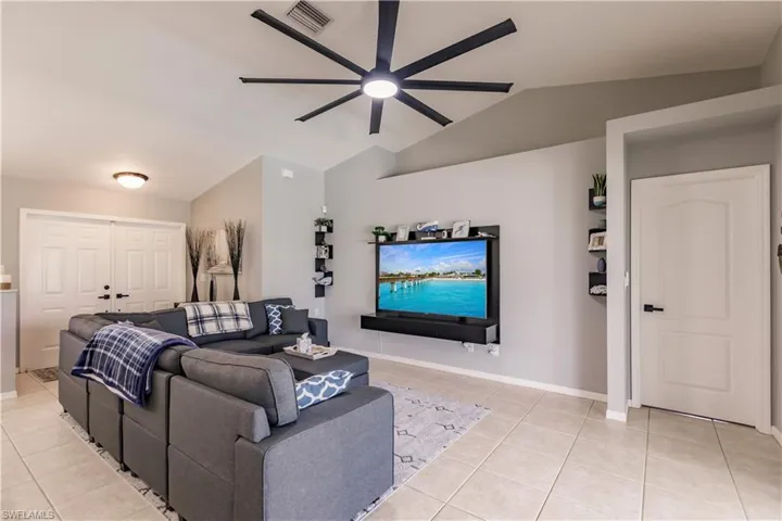 Tiled living room featuring ceiling fan and vaulted ceiling