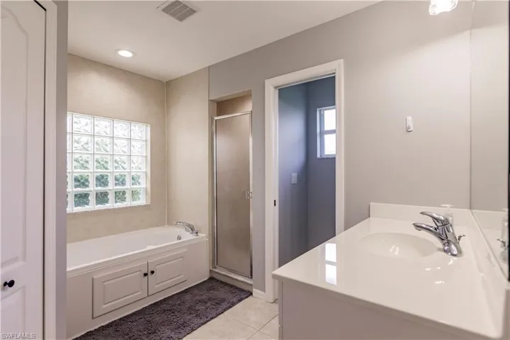 Bathroom with shower with separate bathtub, tile patterned floors, and vanity