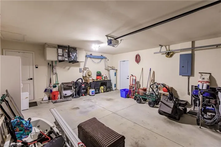 Garage featuring electric water heater, a garage door opener, and electric panel