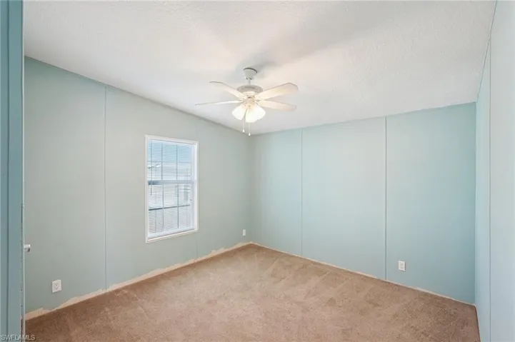 Carpeted empty room with a decorative wall, ceiling fan, and a textured ceiling