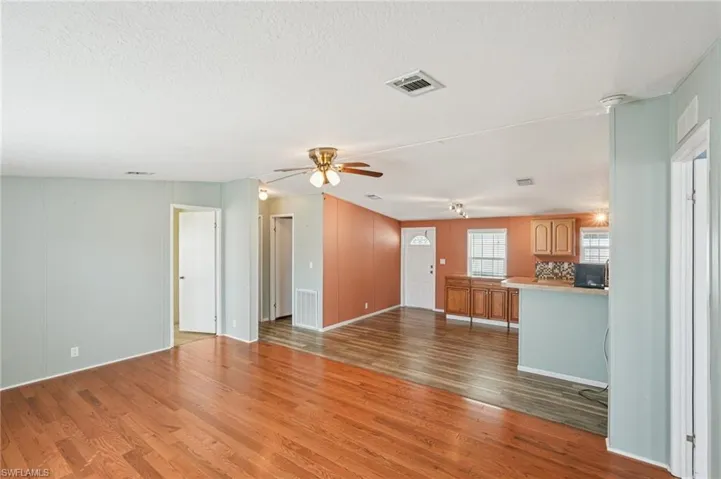 Unfurnished living room featuring a ceiling fan, light wood-type flooring, and a textured ceiling