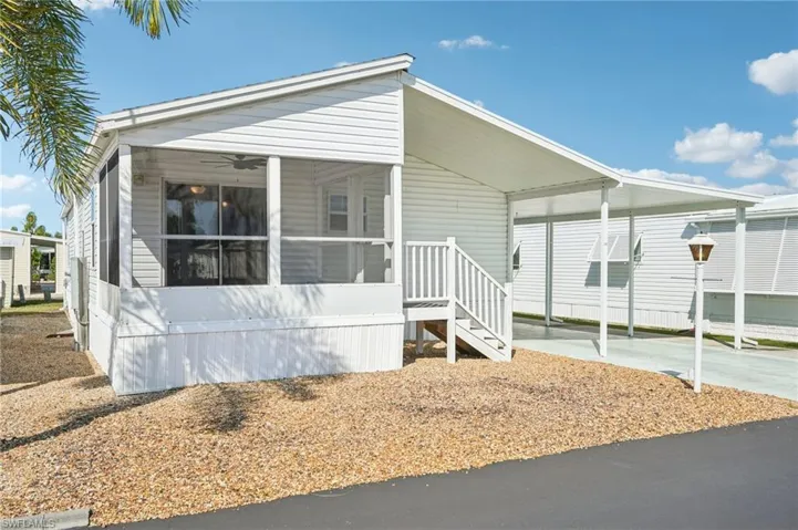 View of front of property featuring an attached carport, a sunroom, and driveway