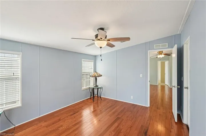 Empty room featuring hardwood / wood-style flooring, a decorative wall, and ceiling fan