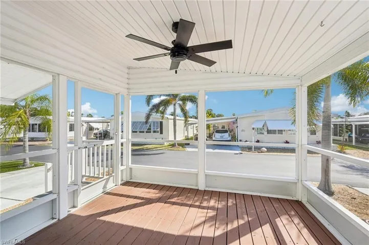 Unfurnished sunroom with a ceiling fan, plenty of natural light, vaulted ceiling, and a wooden deck