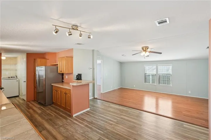 Kitchen featuring light countertops, dark wood-style floors, washer / dryer, freestanding refrigerator, and open floor plan