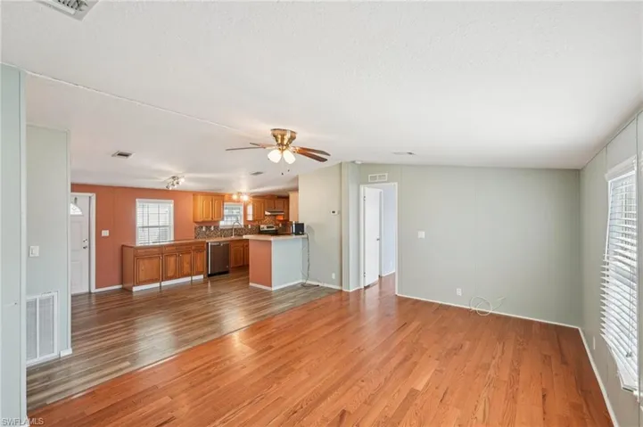 Unfurnished living room with light wood-type flooring, ceiling fan, and a textured ceiling