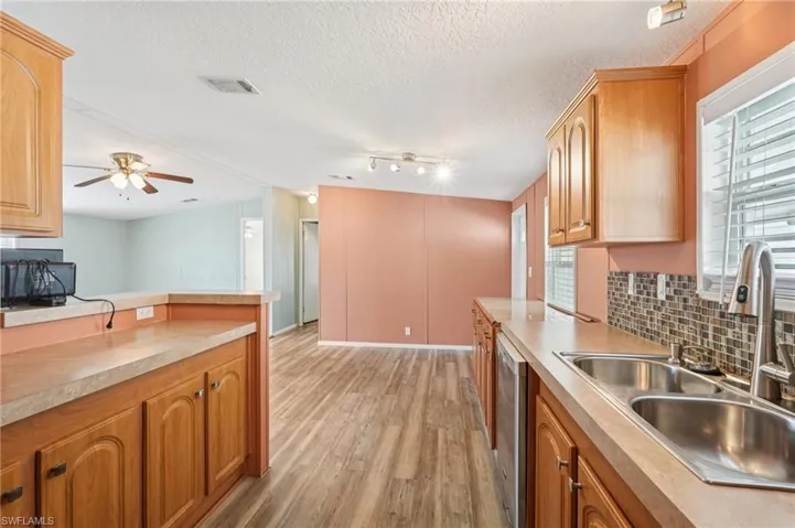 Kitchen with light wood finished floors, light countertops, a textured ceiling, ceiling fan, and decorative backsplash