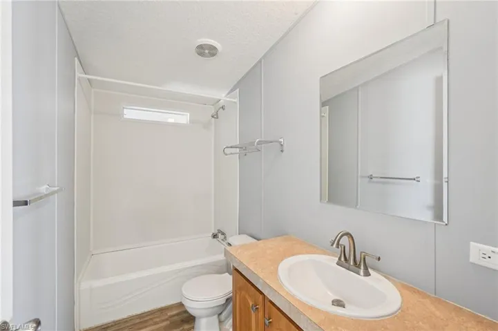 Bathroom with vanity, a textured ceiling, and washtub / shower combination