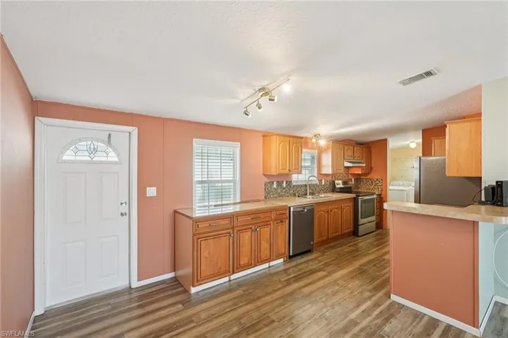 Kitchen featuring a peninsula, a textured ceiling, light countertops, stainless steel appliances, and light wood-style floors