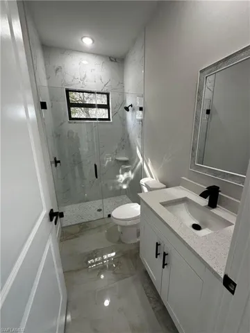 Bathroom featuring vanity, an enclosed shower, and toilet