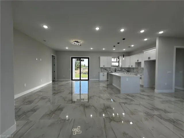 Kitchen with white cabinets, decorative light fixtures, a kitchen island, and decorative backsplash