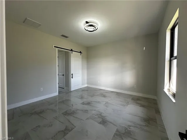 Unfurnished room featuring a barn door and a healthy amount of sunlight