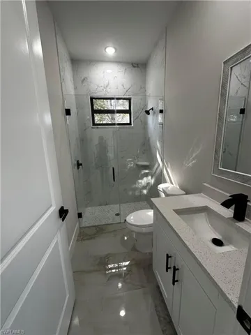 Bathroom with vanity, a shower with door, and toilet