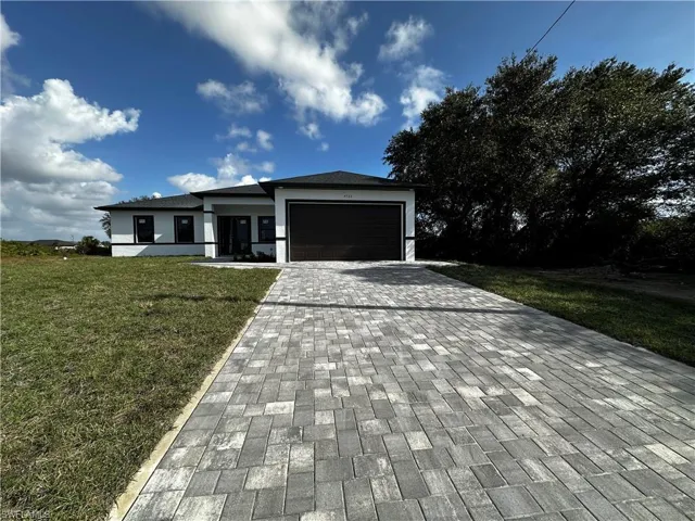 View of front of property featuring a garage and a front yard
