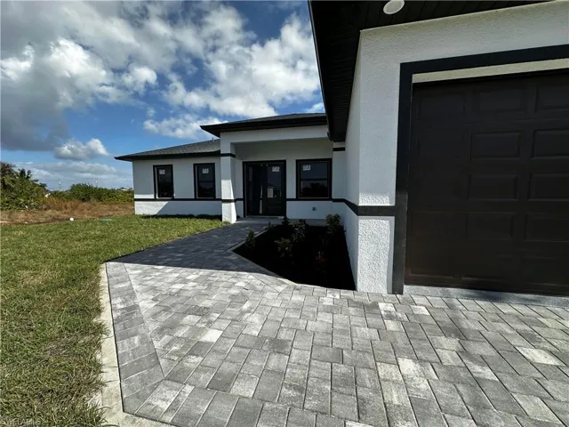 Doorway to property featuring a lawn and a garage