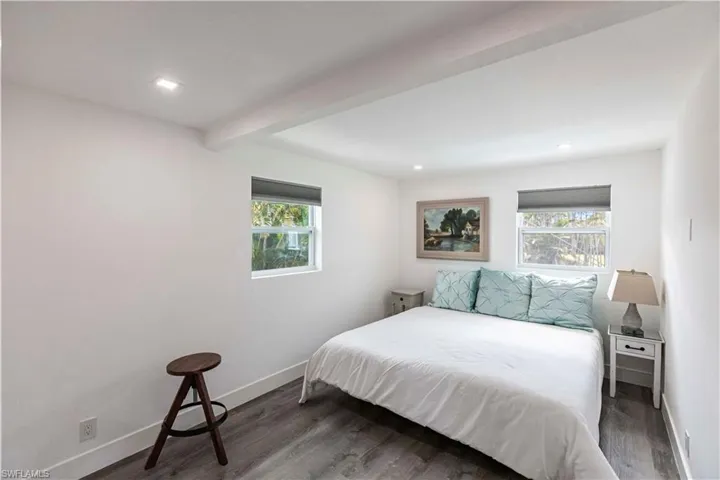 Room featuring white walls, recessed lighting, two windows with roller shades, and wood-finish flooring