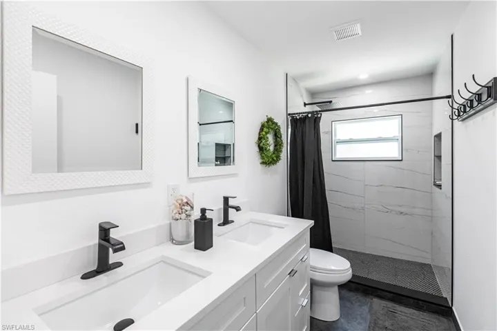 Dual vanity with integrated sinks and matte black fixtures, set against white cabinetry