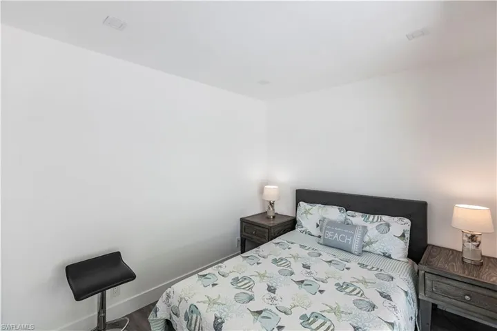Recessed ceiling lighting, white walls, and dark wood-finish flooring