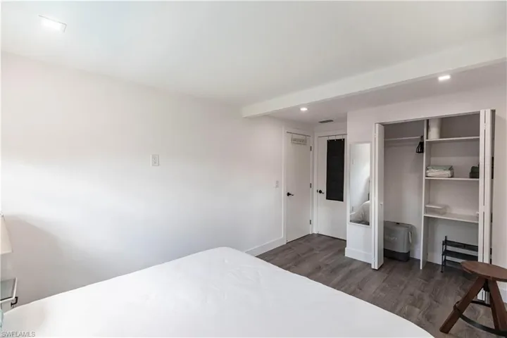 Bedroom featuring wood-finish flooring, recessed lighting, white walls, and a built-in closet with shelving
