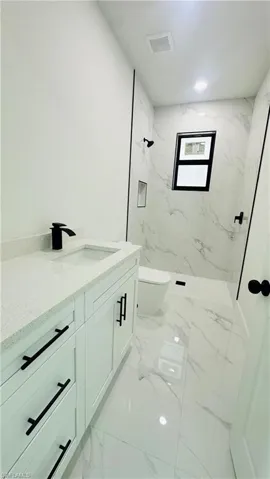 Full bath featuring vanity and a marble finish shower