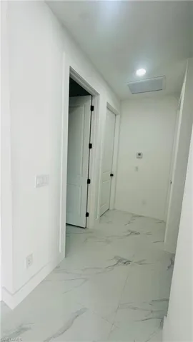 Hallway featuring attic access and baseboards
