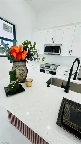Kitchen with white cabinets, stainless steel appliances, and light stone countertops