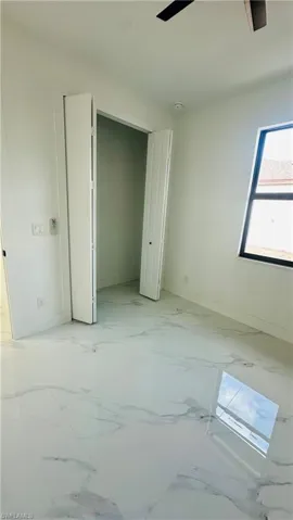 Unfurnished bedroom featuring a closet, ceiling fan, and light marble finish flooring
