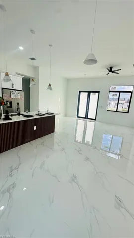 Kitchen with pendant lighting, stainless steel fridge with ice dispenser, open floor plan, and white cabinets