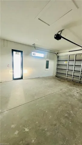 Garage with concrete block wall, electric panel, and a garage door opener