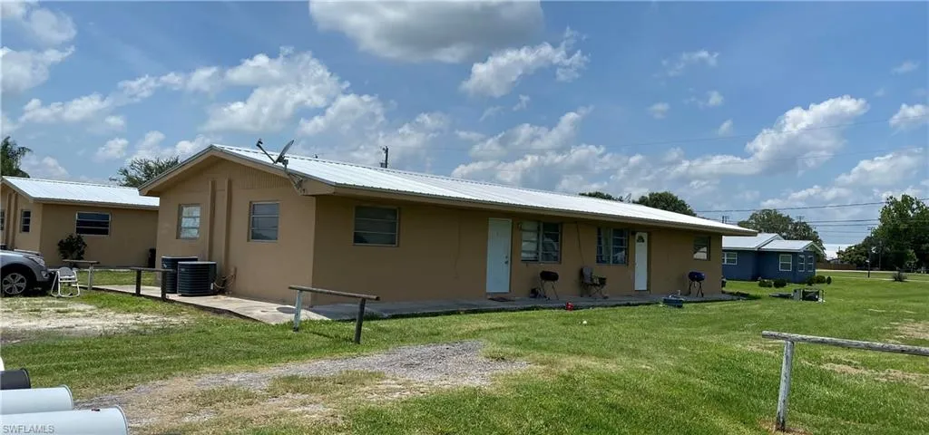 View of front of home featuring a front lawn, metal roof, stucco siding, and fence