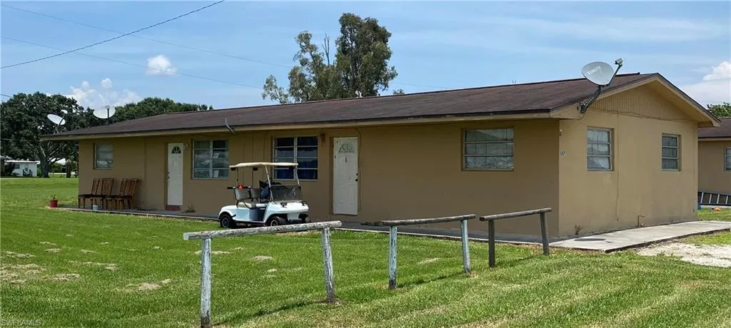 Rear view of house featuring stucco siding, fence, and a yard