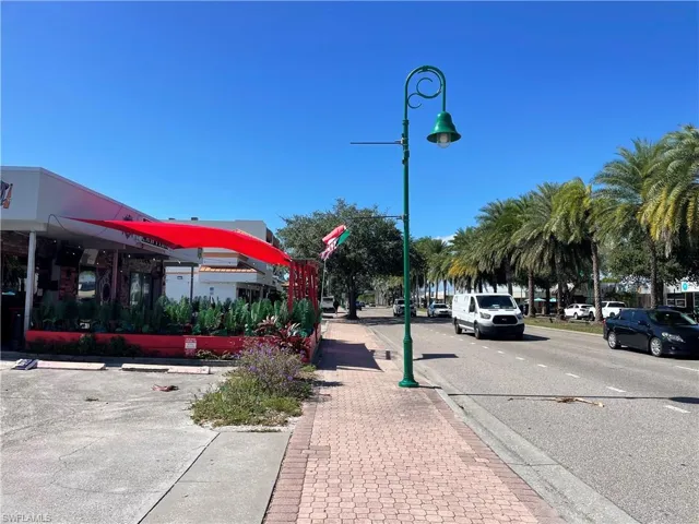View of asphalt road featuring sidewalks and curbs