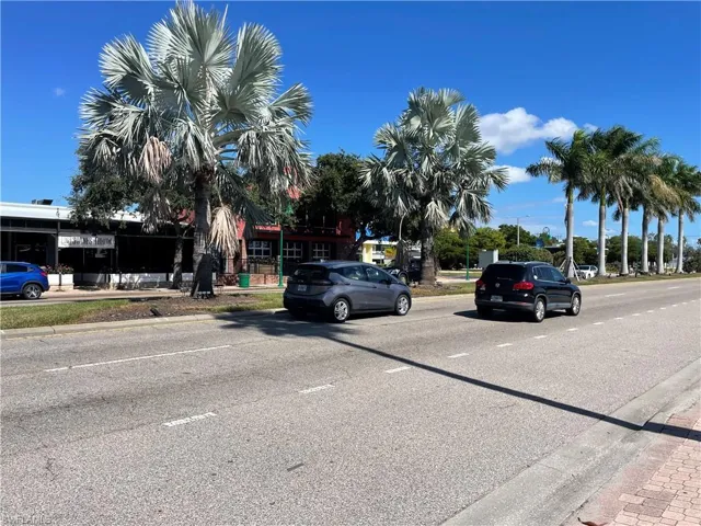 View of asphalt road featuring curbs and street lights