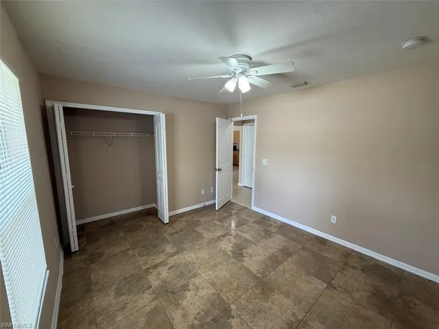 Unfurnished bedroom with a closet, baseboards, and a ceiling fan