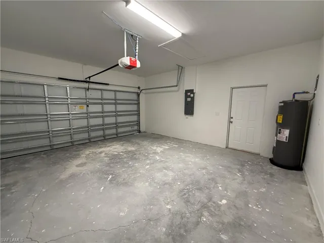 Garage featuring water heater, electric panel, and a garage door opener
