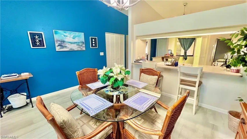Dining room featuring high vaulted ceiling, an inviting chandelier, and light hardwood / wood-style floors