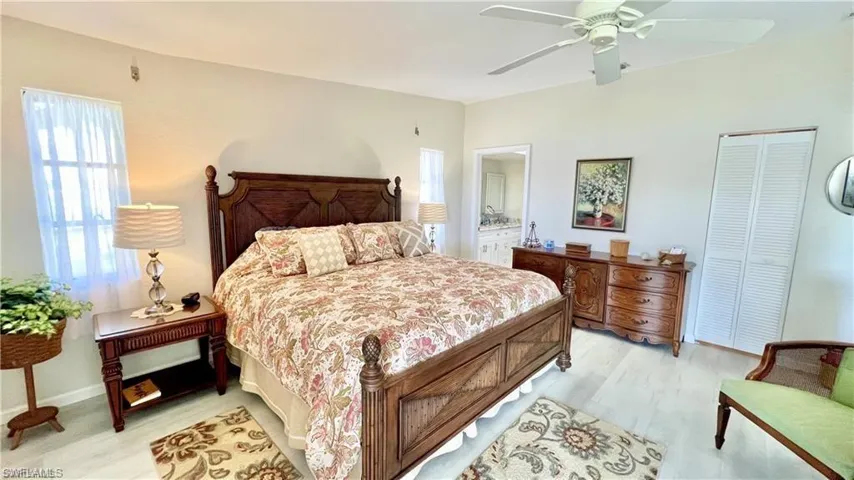 Bedroom featuring connected bathroom, light hardwood / wood-style floors, a closet, and ceiling fan