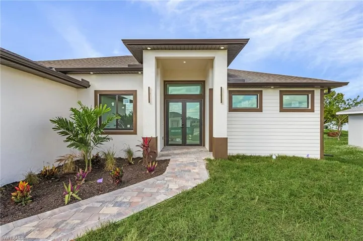 View of exterior entry with a lawn and french doors