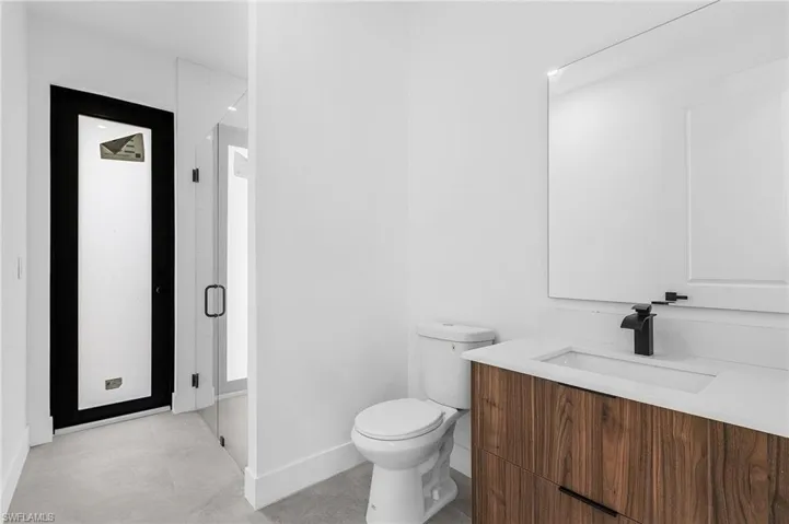 Bathroom featuring vanity, toilet, and an enclosed shower