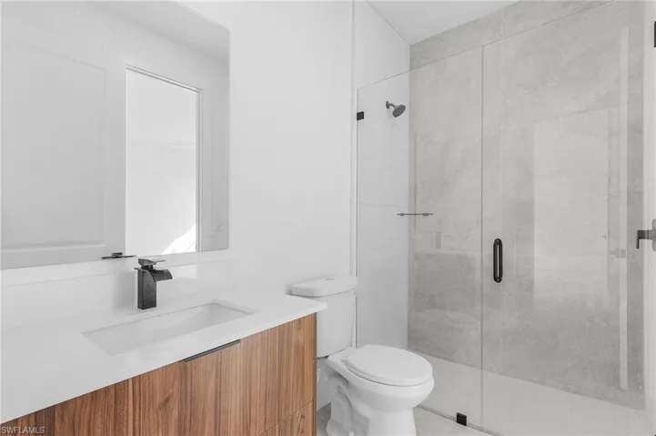 Bathroom featuring vanity, a shower with shower door, and toilet