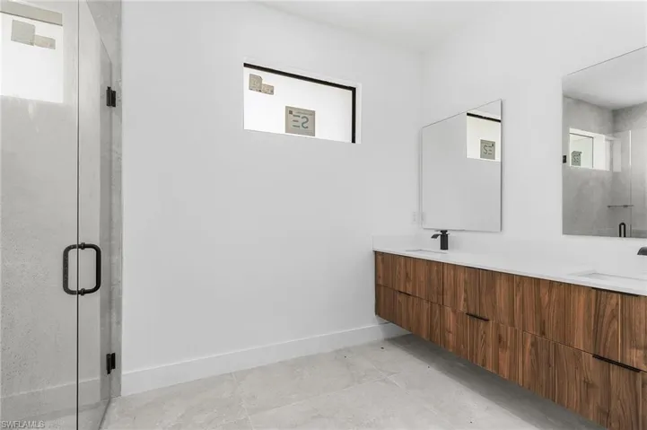 Bathroom featuring vanity, tile patterned floors, and a shower with shower door
