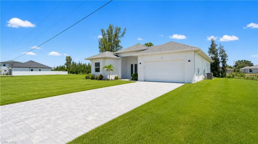 Contemporary residence featuring a light-colored exterior, an integrated garage, and a paver driveway