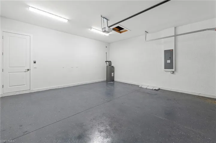 Spacious garage featuring a durable epoxy-coated floor, bright overhead fluorescent lighting, and a solid panel interior door