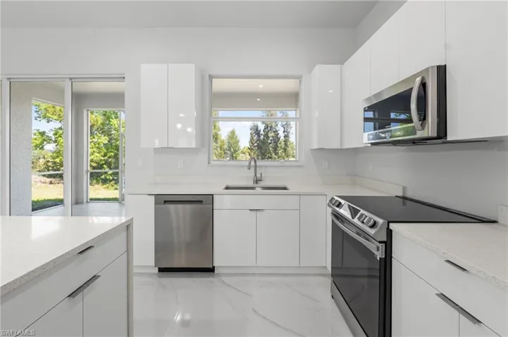 Modern kitchen featuring white cabinetry, light-toned countertops, stainless steel appliances, and tile flooring