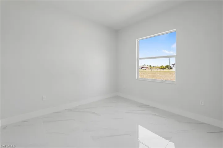 Bright interior space featuring white walls, white baseboards, and large format white tile flooring with subtle veining