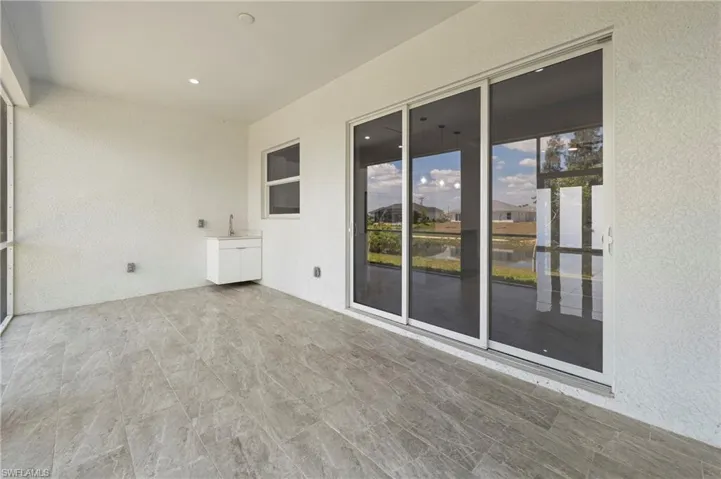 Screened outdoor living area featuring large format tile flooring, a built-in sink with cabinetry, overhead lighting, and expansive sliding glass doors