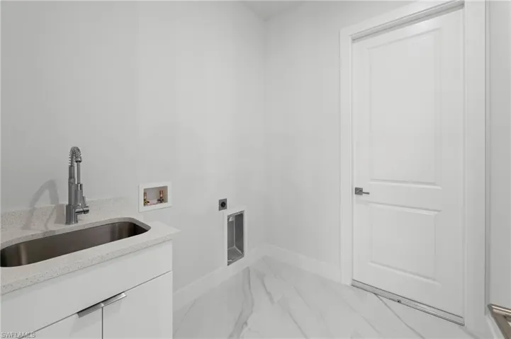 Utility room with a built-in sink vanity, stone-finish countertop, and stainless steel undermount sink with a pull-down faucet