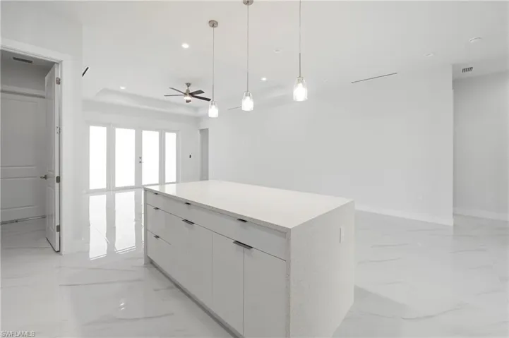 Contemporary kitchen island featuring a light-colored solid surface countertop and white flat-panel cabinetry