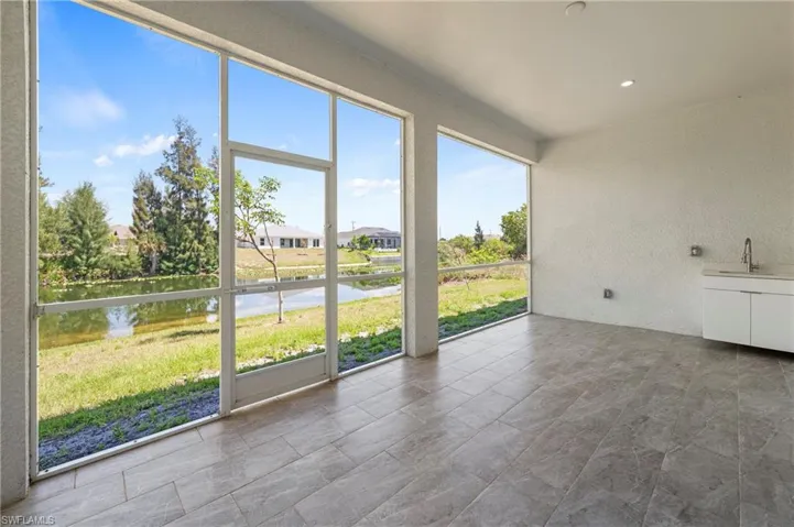 Screened outdoor living area featuring a water view, large format tile flooring, recessed lighting, and an integrated outdoor sink with cabinetry